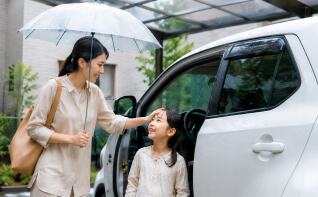 雨の日にカーポートで車から降りる親子